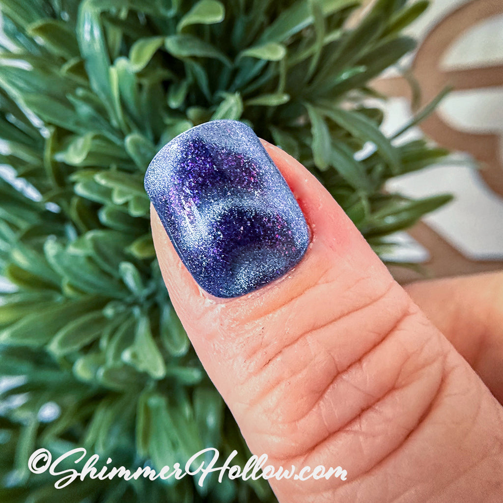An example picture on a short fingernail in purple nail polish with shimmering chevron shapes. 